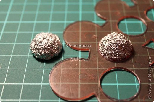 Не знаю как правильно называются штучки, которые находятся на верхушке будильника, поэтому назову их просто - звоночки. Так вот возьмем фольгу и сформируем из неё две полусферы. Чтобы они получились одинакового диаметра воспользуемся линейкой с кружочками. (фото 6)