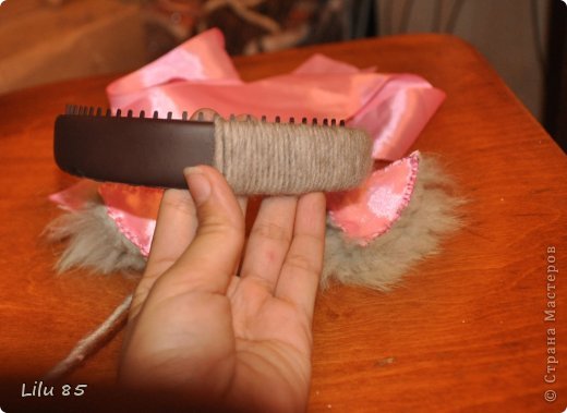 Вам понадобятся: любая пластиковая бутылка, клейкая лента, ножницы, серая и розовая лента, вата, широкий ободок, толстая серая шерстяная нить, клеевой пистолет, старый серый меховой воротник или другой мех. Украсьте углы цветами или лентами разных цветов. Для начала разрежьте пластиковую бутылку на два квадрата. Скрутите квадраты, чтобы получилась плюшевая игрушка, и прикрепите ее липкой лентой. С первого раза может не получиться, поэтому покрутите и отпустите квадратики несколько раз, чтобы 