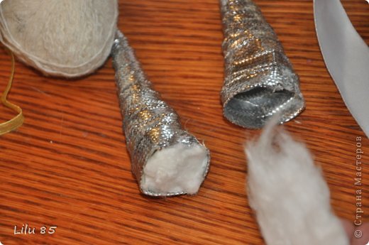 Вам понадобятся: любая пластиковая бутылка, липкая лента, ножницы, серая и розовая лента, вата, широкий ободок, толстая серая шерстяная нить, клеевой пистолет, старый серый меховой воротник или другой мех. Украсьте углы цветами или лентами разных цветов. Для начала разрежьте пластиковую бутылку на два квадрата. Скрутите квадраты, чтобы получилась плюшевая игрушка, и прикрепите ее липкой лентой. С первого раза может не получиться, поэтому покрутите и отпустите квадратики несколько раз, чтобы 