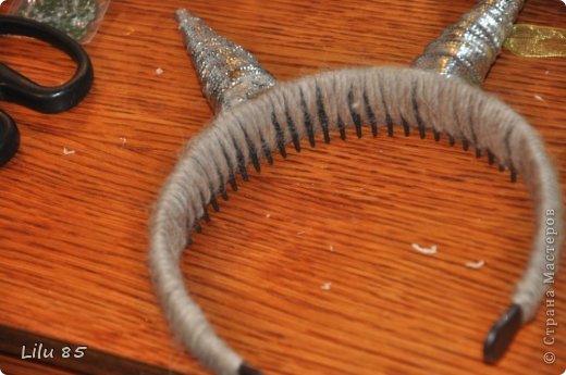 Для изготовления рожек для вашей козы вам понадобятся: любая пластиковая бутылка, клейкая лента, ножницы, серая и розовая лента, вата, обруч, желательно широкий, толстая серая шерстяная нить, клеевой пистолет, старый серый меховой воротник или другой мех. Украсьте углы цветами или лентами разных цветов. Сначала разрежьте пластиковую бутылку на два квадрата. Скрутите квадраты в 