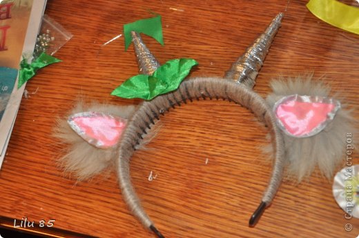 Для изготовления рожек для козы нам понадобятся: любая пластиковая бутылка, липкая лента, ножницы, серая и розовая лента, вата, обруч, желательно широкий, толстая серая шерстяная нить, клеевой пистолет, старый серый меховой воротник или другой мех. Украсьте углы цветами или лентами разных цветов. Сначала разрежьте пластиковую бутылку на два квадрата. Скрутите квадраты в 