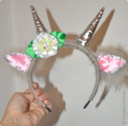 Для изготовления рожек для козы нам понадобятся: любая пластиковая бутылка, липкая лента, ножницы, серая и розовая лента, вата, обруч, желательно широкий, толстая серая шерстяная нить, клеевой пистолет, старый серый меховой воротник или другой мех. Украсьте углы цветами или лентами разных цветов. Для начала разрежьте пластиковую бутылку на два квадрата. Скрутите квадраты, чтобы получилась плюшевая игрушка, и прикрепите ее липкой лентой. С первого раза может не получиться, поэтому покрутите и отпустите квадратики несколько раз, чтобы 